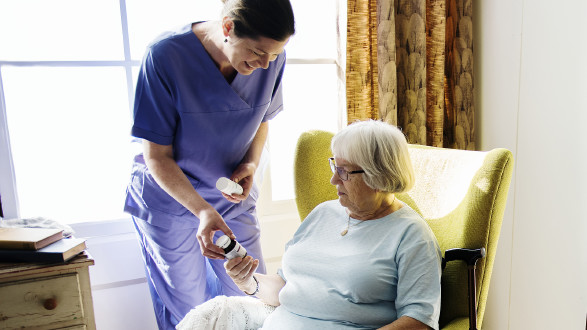 Pflegerin zeigt Patientin Medikament